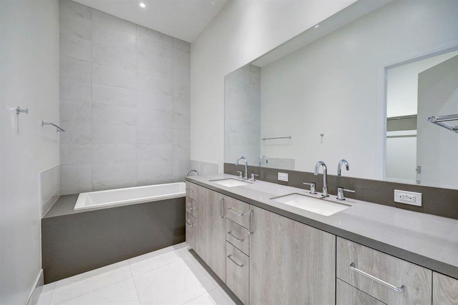 Relax and unwind in the primary bath's deep soaking tub surrounded by floor-to-ceiling tile and polished chrome fixtures.