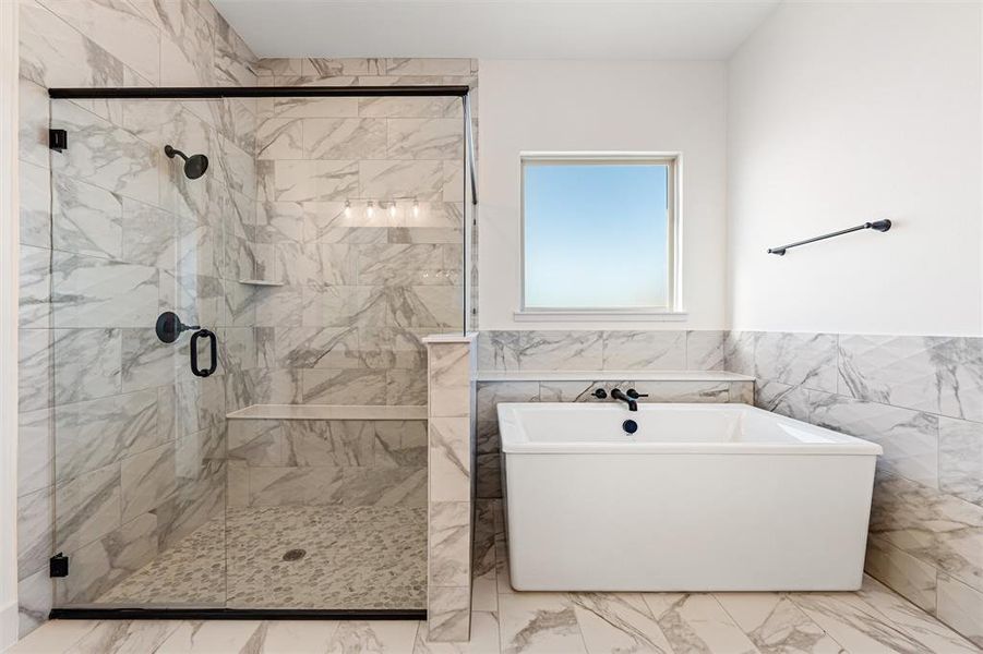 Full bath featuring tile walls, a wainscoted wall, a marble finish shower, a soaking tub, and marble finish flooring