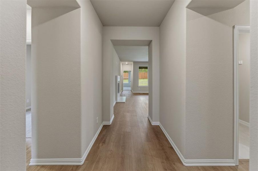 Hallway featuring wood-finish flooring, light neutral wall paint, and white baseboards