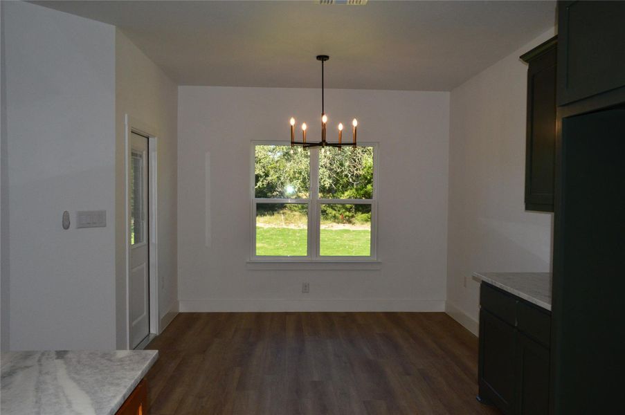 Unfurnished dining area with a chandelier and dark wood-style floors Unfurnished dining area with a chandelier and dark wood-style floors