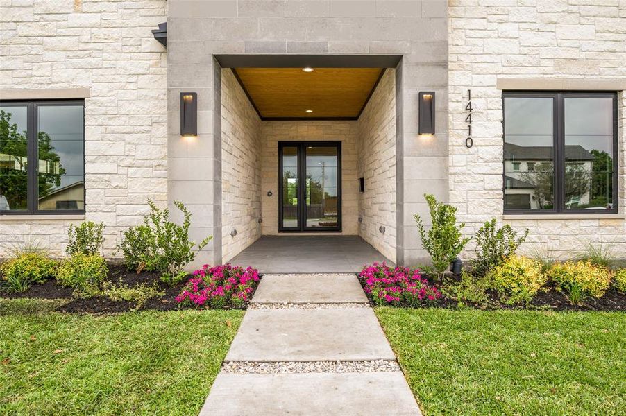 Contemporary stone facade featuring a recessed entry, double glass doors, and a wood-finish ceiling on the porch