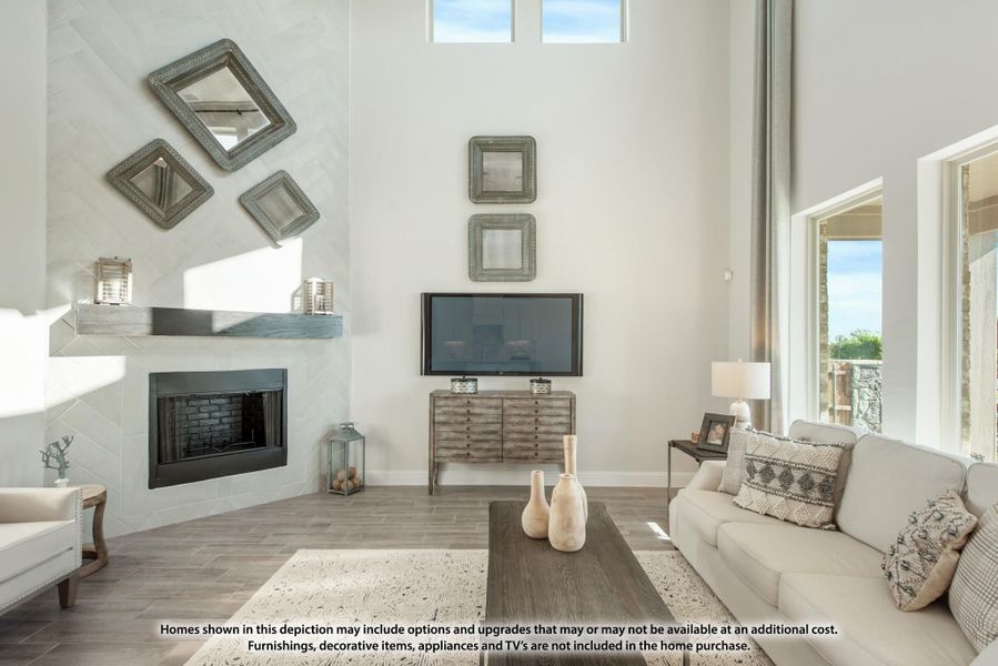 Living room with high ceilings, white fireplace, wood floors, and neutral sofa near large windows