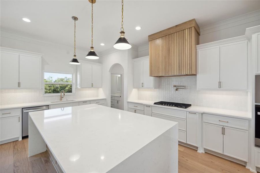 Kitchen with stainless steel appliances, decorative light fixtures, light hardwood / wood-style flooring, a kitchen island, and white cabinets