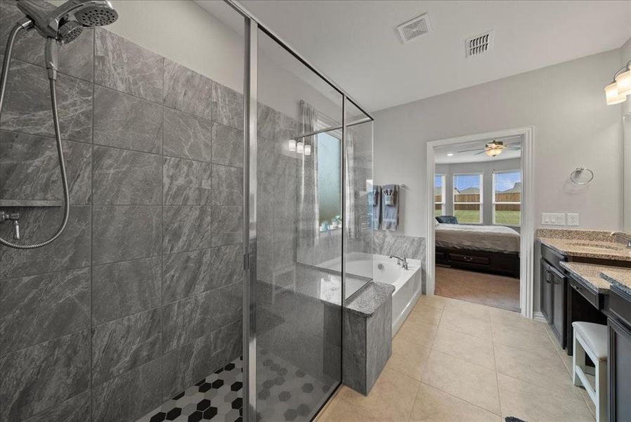 Primary Bathroom with custom tile patterned floors, separate shower and tub, and vanity.