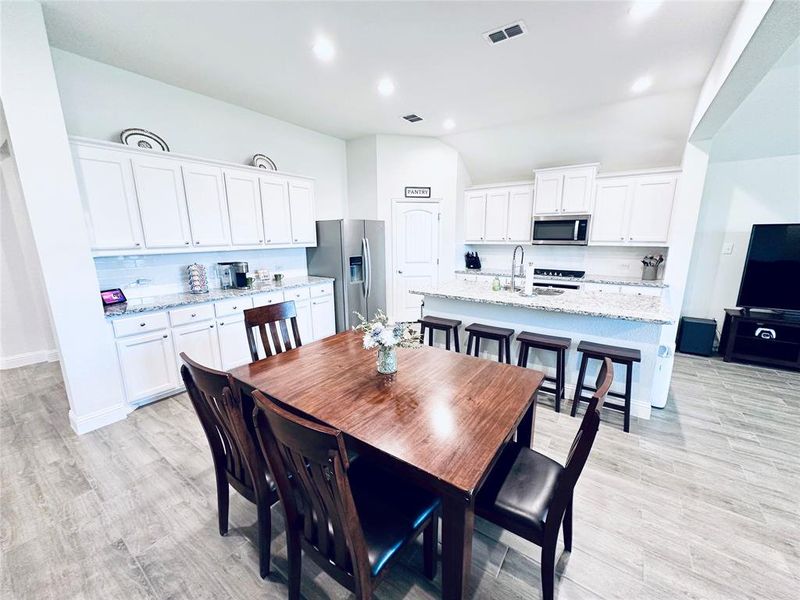 Dining space with sink, light hardwood / wood-style flooring, and vaulted ceiling