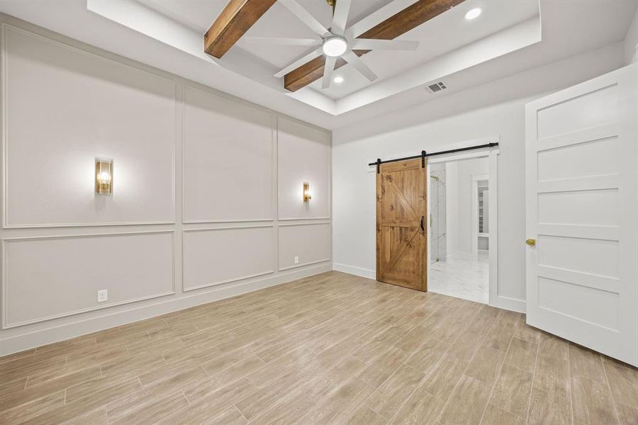 Spacious room featuring wood-finish flooring and an accent wall with wainscoting details and wall sconces