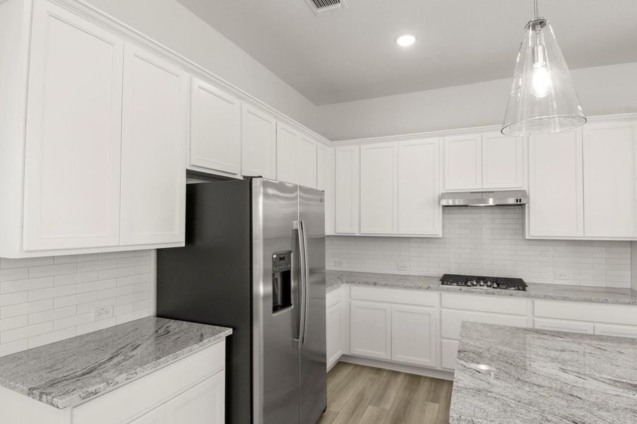 Kitchen with backsplash, white cabinets, light stone countertops, and recessed lighting