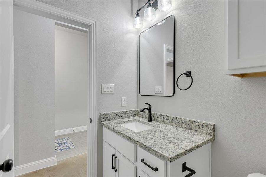 Half bathroom with a textured wall and vanity