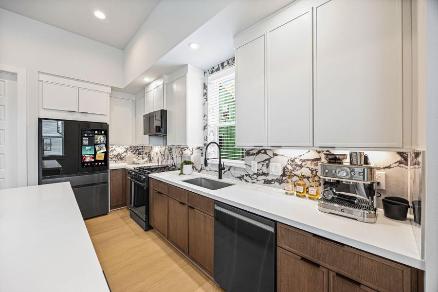 Sleek and modern kitchen featuring state-of-the-art appliances, elegant cabinetry, and a striking marble backsplash. **Model of similar home**
