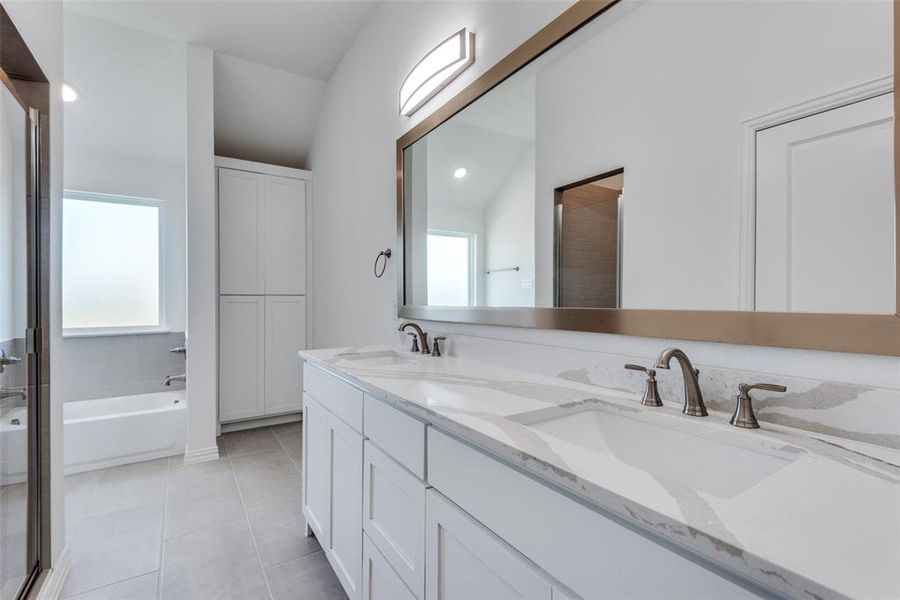 Bathroom with vanity, lofted ceiling, tile patterned floors, and a tub