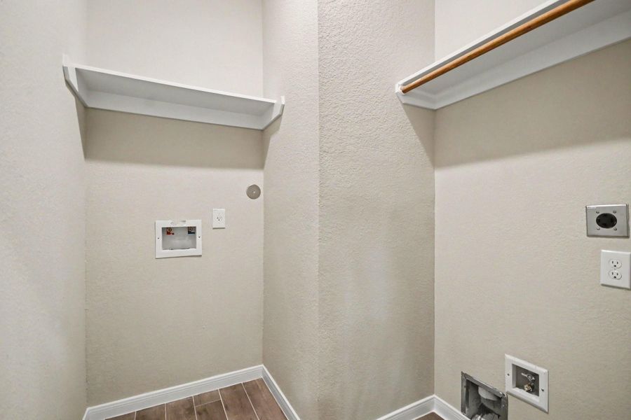 Utility room ready for washer and dryer installation, featuring built-in shelving and convenient hookups.