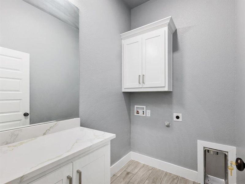 Laundry area with cabinet space, hookup for a gas dryer, hookup for a washing machine, a textured wall, and wood finish floors Laundry area with cabinet space, hookup for a gas dryer, hookup for a washing machine, a textured wall, and wood finish floors