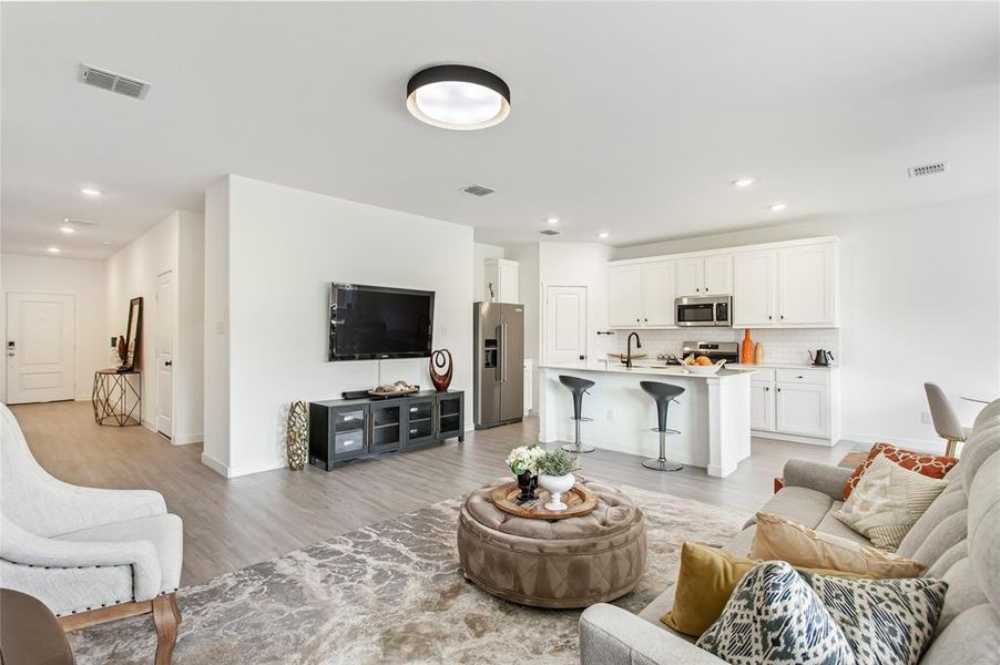 The property features an open-concept living area with light-toned flooring and white walls, illuminated by recessed lighting and a modern ceiling fixture