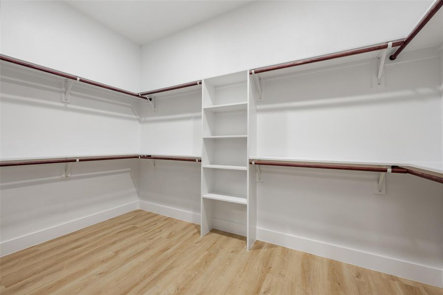 Walk in closet with light wood-style floors Walk in closet with light wood-style floors