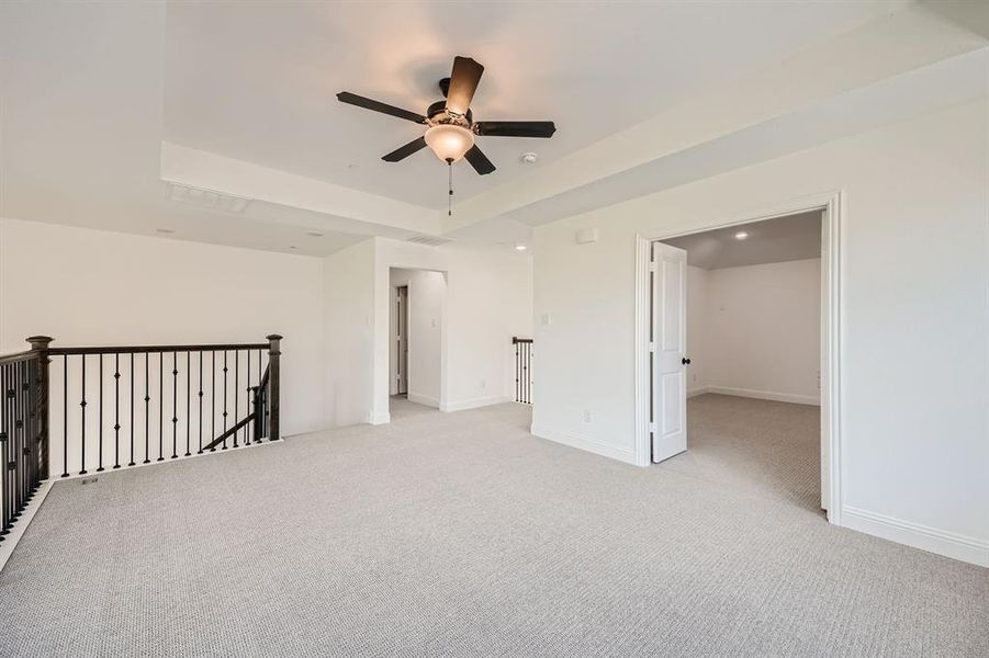 Spare room with a tray ceiling, ceiling fan, and light colored carpet