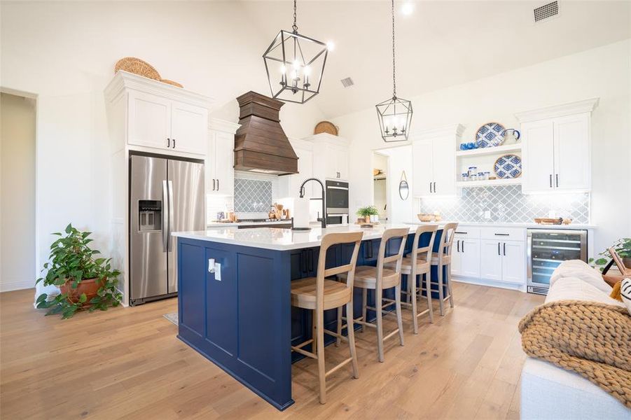 Kitchen featuring dual tone cabinetry, stainless steel appliances, a kitchen island with sink, beverage cooler, and a kitchen breakfast bar Kitchen featuring dual tone cabinetry, stainless steel appliances, a kitchen island with sink, beverage cooler, and a kitchen breakfast bar