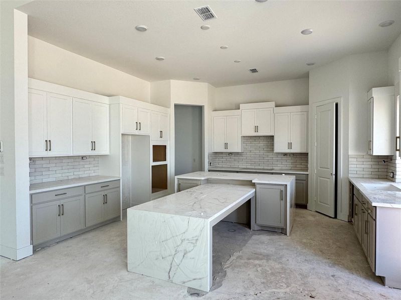 Additional view of the kitchen which offers an abundance of cabinets and a unique breakfast bar.