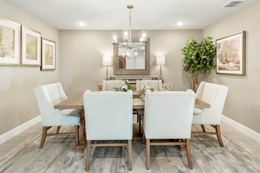 Dining room with wood table, six white upholstered chairs, and a chandelier overhead