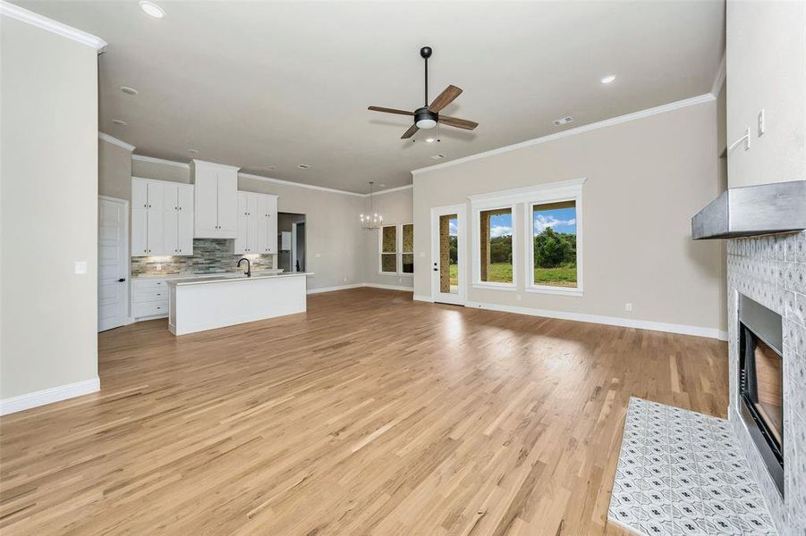 Unfurnished living room featuring crown molding, sink, light wood-type flooring, and ceiling fan