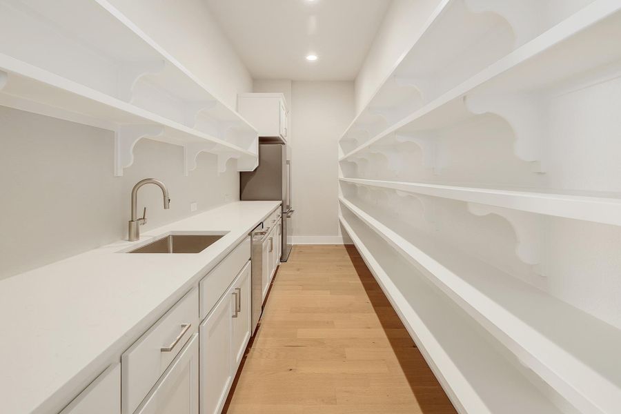 A well-appointed butler's pantry with vast shelving, extra refrigerator, plumbed ice-maker, and prep sink.