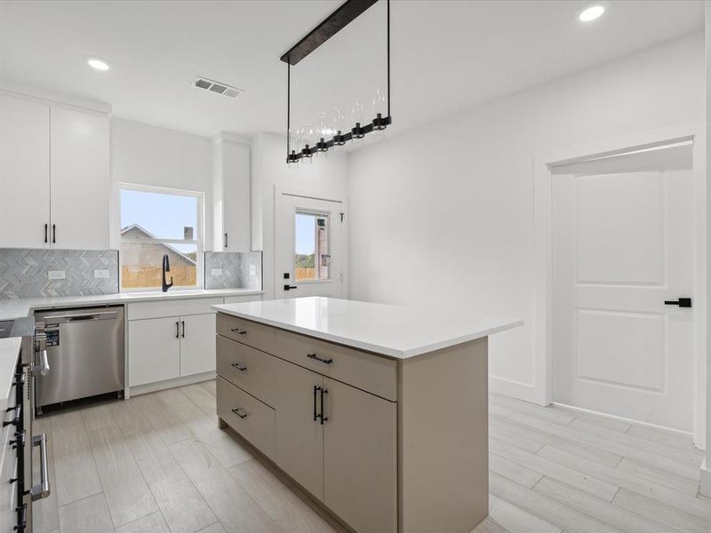 Kitchen with decorative backsplash, stainless steel dishwasher, a kitchen island, decorative light fixtures, and white cabinetry