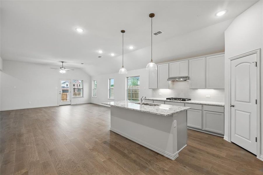 Kitchen with lofted ceiling, recessed lighting, dark wood-style floors, a center island with sink, and decorative backsplash Kitchen with lofted ceiling, recessed lighting, dark wood-style floors, a center island with sink, and decorative backsplash