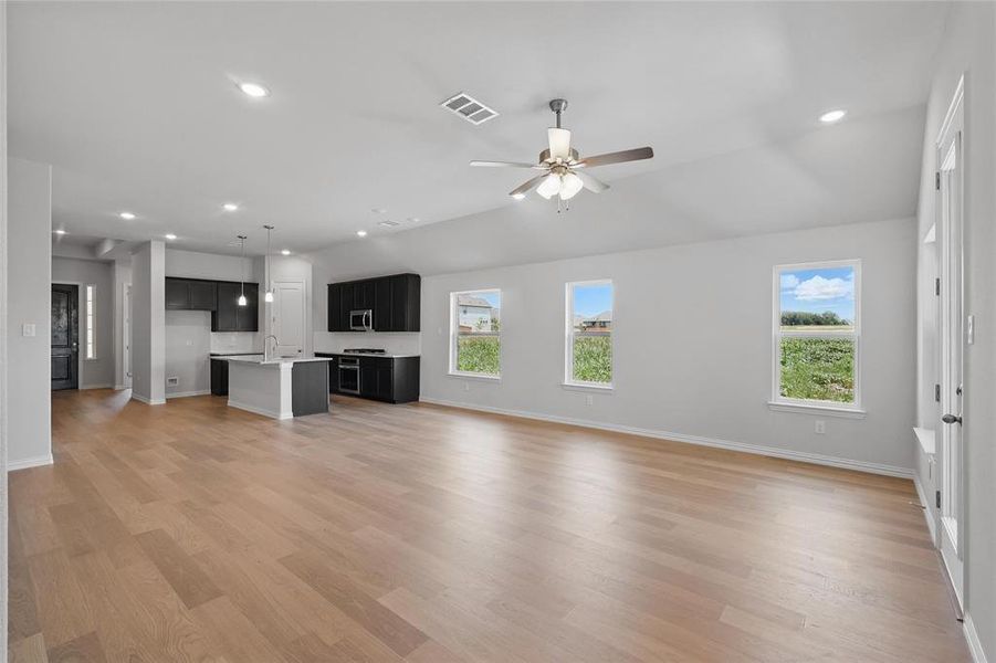 Unfurnished living room featuring baseboards, light wood-style flooring, ceiling fan, recessed lighting, and a sink