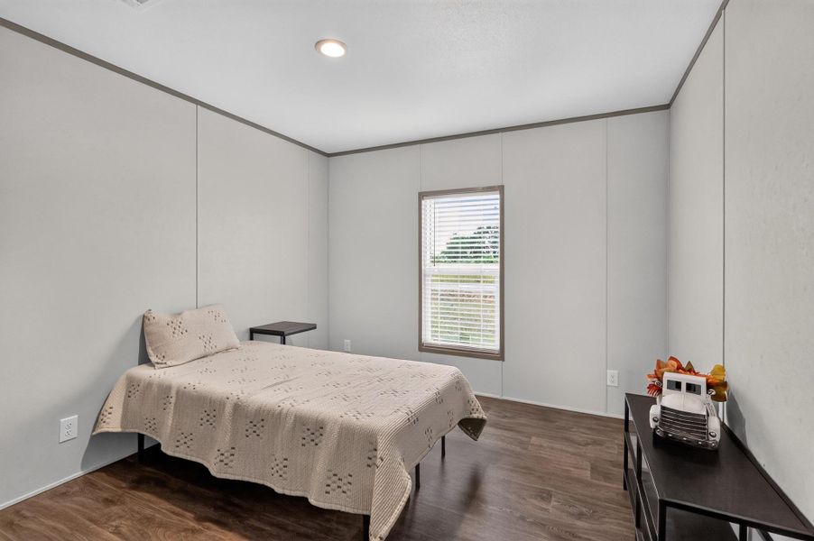 A well-lit bedroom features rich wood flooring, offering a peaceful retreat.