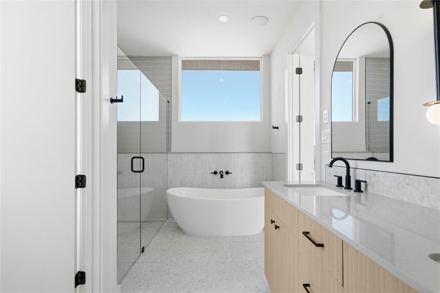 Full bath featuring a freestanding bath, double vanity, a stall shower, a wainscoted wall, and tile walls Full bath featuring a freestanding bath, double vanity, a stall shower, a wainscoted wall, and tile walls