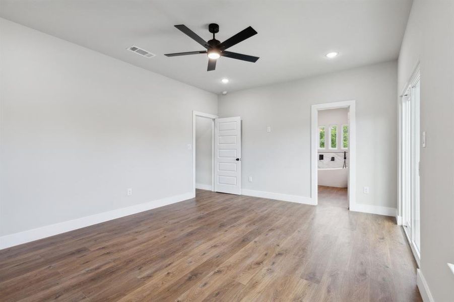 Unfurnished bedroom with connected bathroom, wood-type flooring, and ceiling fan