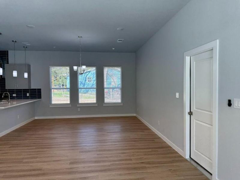 This stunning view captures the elegant living room seamlessly flowing into the inviting dining area, complemented by a chic, modern kitchen situated harmoniously to the side.