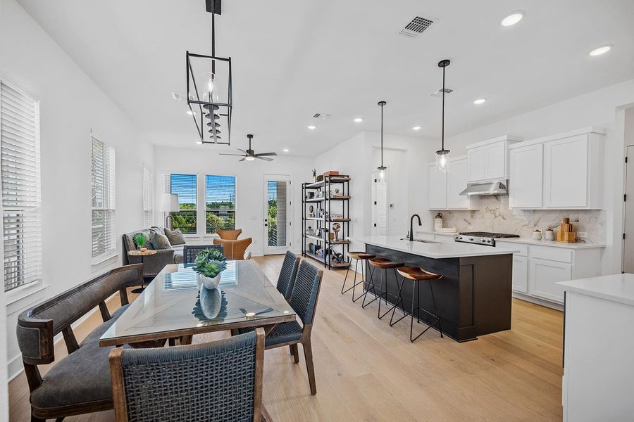 Open floor plan with dining area, center island with breakfast area and living room looking out to green space.