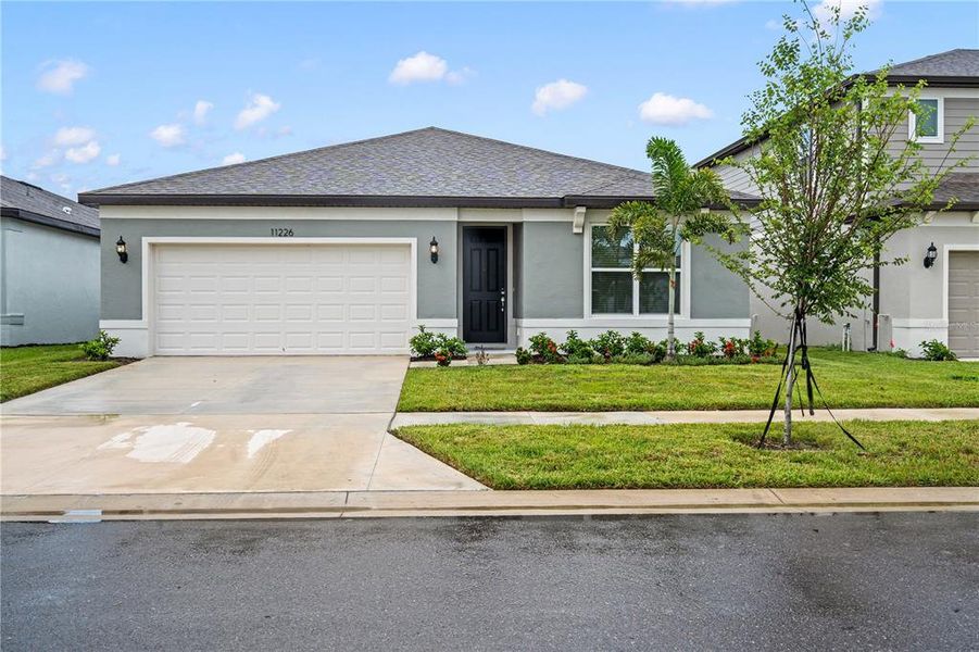 Front exterior of a new home in Evergreen, Thonotosassa, FL, highlighting curb appeal (Image 1). Front exterior of a new home in Evergreen, Thonotosassa, FL, highlighting curb appeal (Image 1).