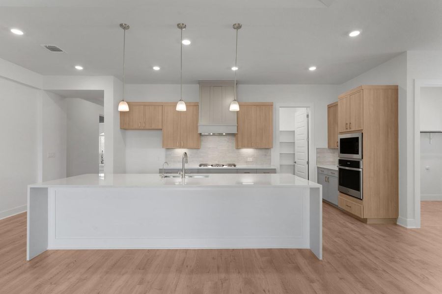 A pristine kitchen features a spacious island with a breakfast bar, complemented by modern appliances and sleek cabinetry.