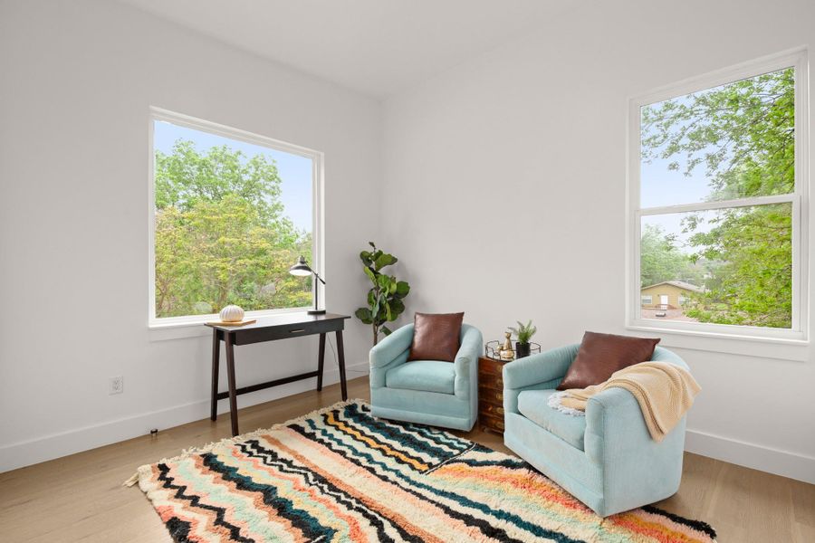 Bright room featuring two large windows with white frames, light wood-finish flooring, and crisp white walls