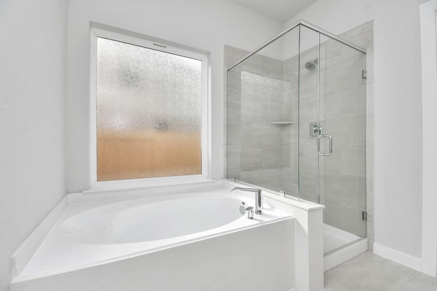Indulge in a spa-like retreat within the confines of this primary bathroom. Delight in a spacious walk-in shower enveloped in stylish tile surround and unwind in a separate garden tub adorned with custom detailing. Indulge in a spa-like retreat within the confines of this primary bathroom. Delight in a spacious walk-in shower enveloped in stylish tile surround and unwind in a separate garden tub adorned with custom detailing.