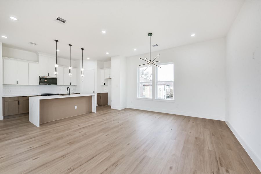 The living room opens up to the dining room showcasing a sleek and modern light fixture.