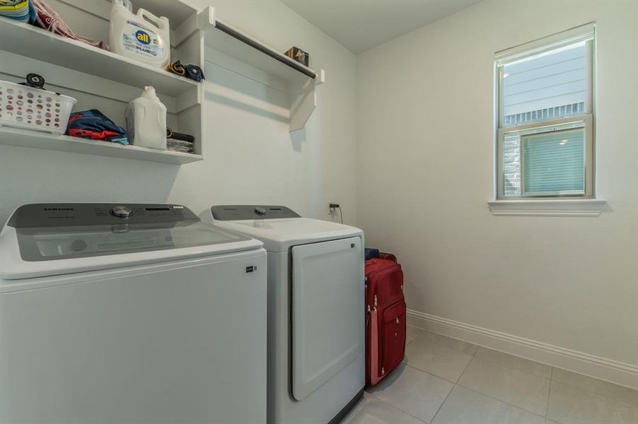Laundry room featuring tiled flooring, built-in shelving, and a single window with blinds