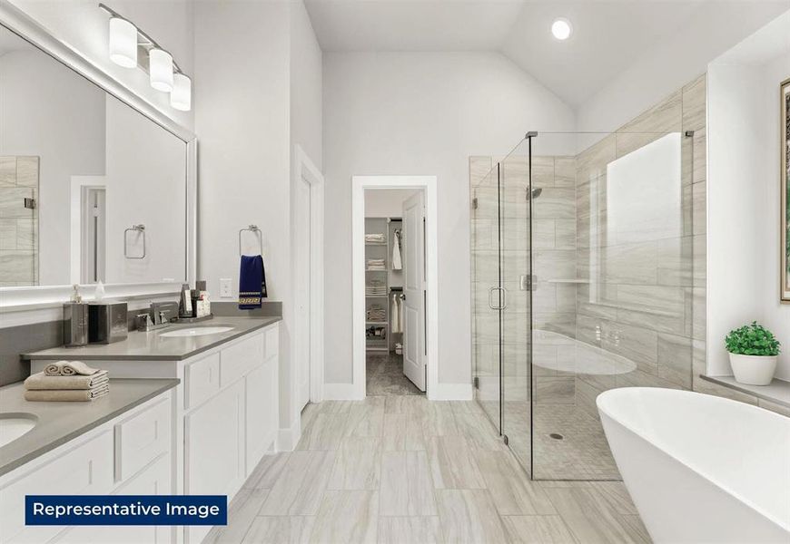 Bathroom with double vanity, a stall shower, a freestanding tub, vaulted ceiling, and a spacious closet