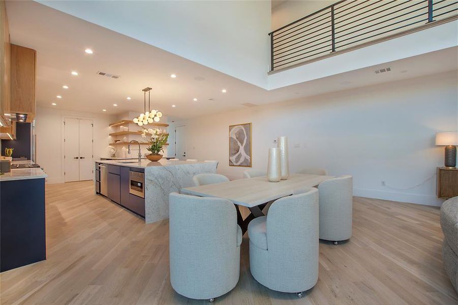 Dining area featuring light wood-type flooring, sink, and a towering ceiling