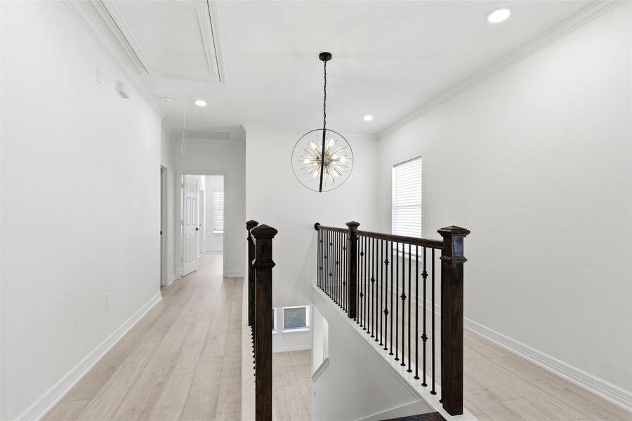 Second floor hallway with black iron railing and pendant lighting leading to bedrooms.