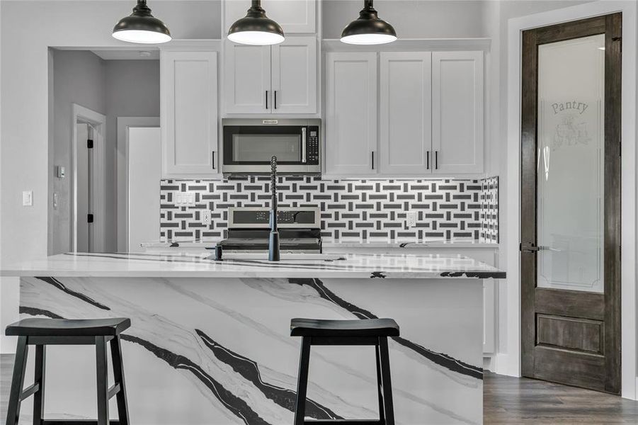 Kitchen featuring stainless steel appliances, light stone counters, decorative backsplash, dark hardwood / wood-style floors, and white cabinetry