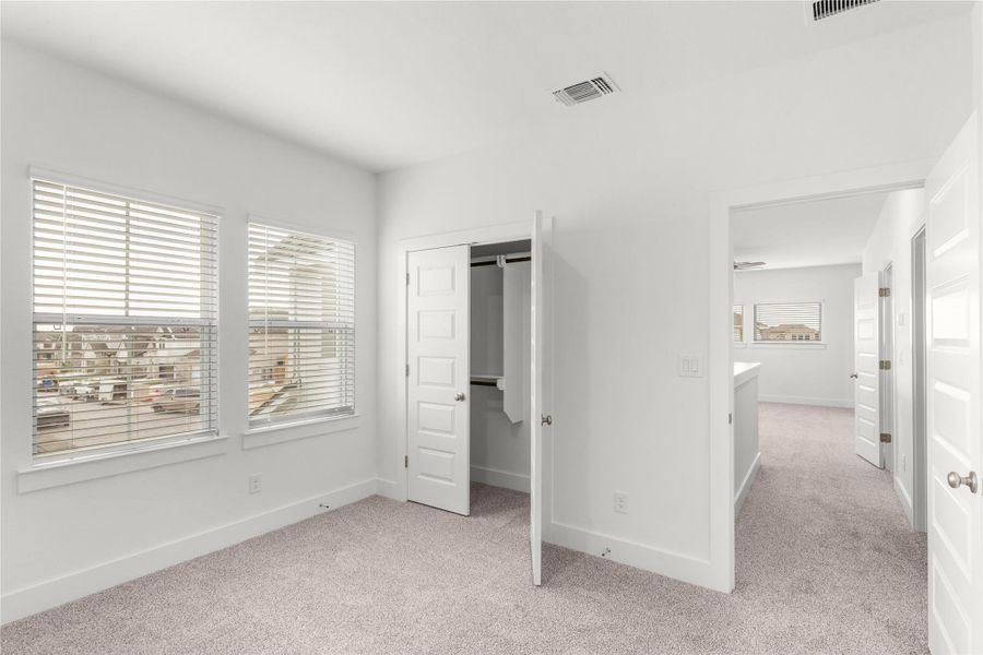 Unfurnished bedroom featuring light colored carpet, multiple windows, and a closet