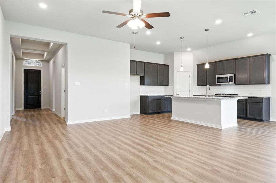 Kitchen featuring light wood finished floors, backsplash, recessed lighting, a kitchen island with sink, and ceiling fan