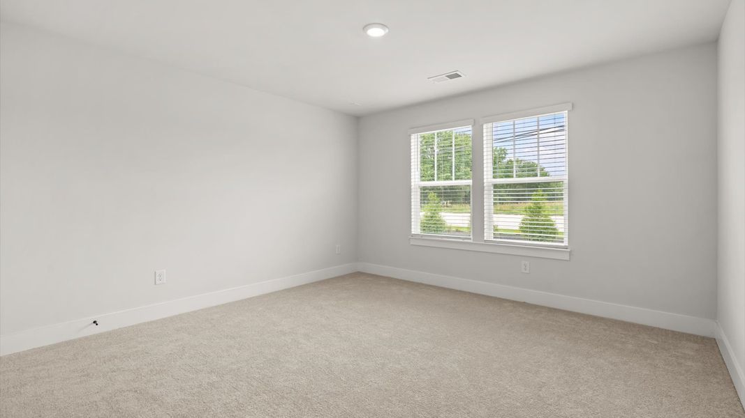 Bright and serene bedroom with comfortable carpeted flooring and large windows for vibrant light