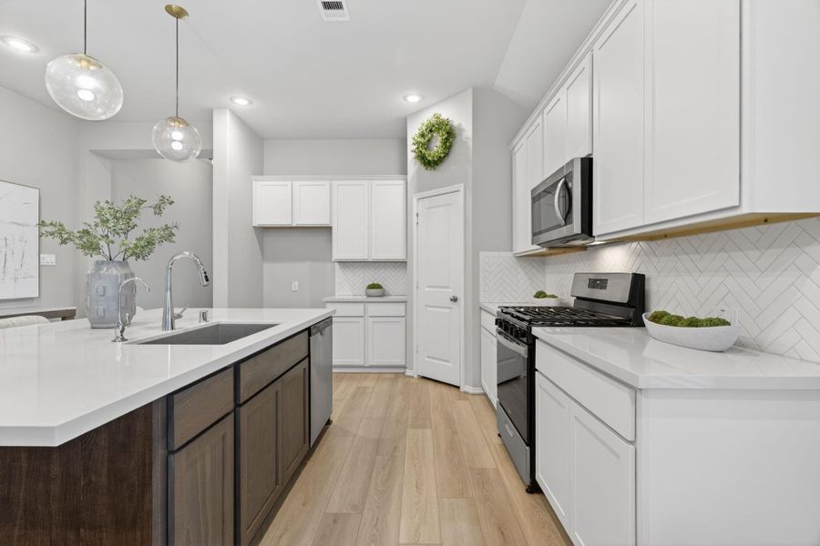 This modern kitchen a stylish herringbone backsplash, and stainless steel appliances. The large island with a dark wood base and quartz countertop offers ample space for cooking and entertaining. This spaces adds warmth and elegance for anyone to love. This modern kitchen a stylish herringbone backsplash, and stainless steel appliances. The large island with a dark wood base and quartz countertop offers ample space for cooking and entertaining. This spaces adds warmth and elegance for anyone to love.