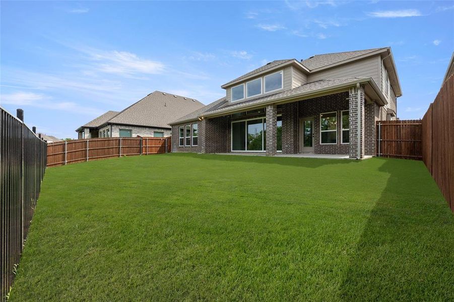 Rear view of property featuring brick siding, a fenced backyard, and a lawn Rear view of property featuring brick siding, a fenced backyard, and a lawn