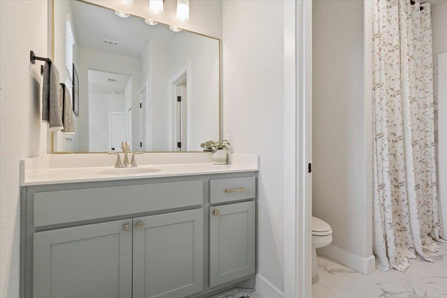 Bathroom with vanity, light marble finish floors, and a shower with curtain