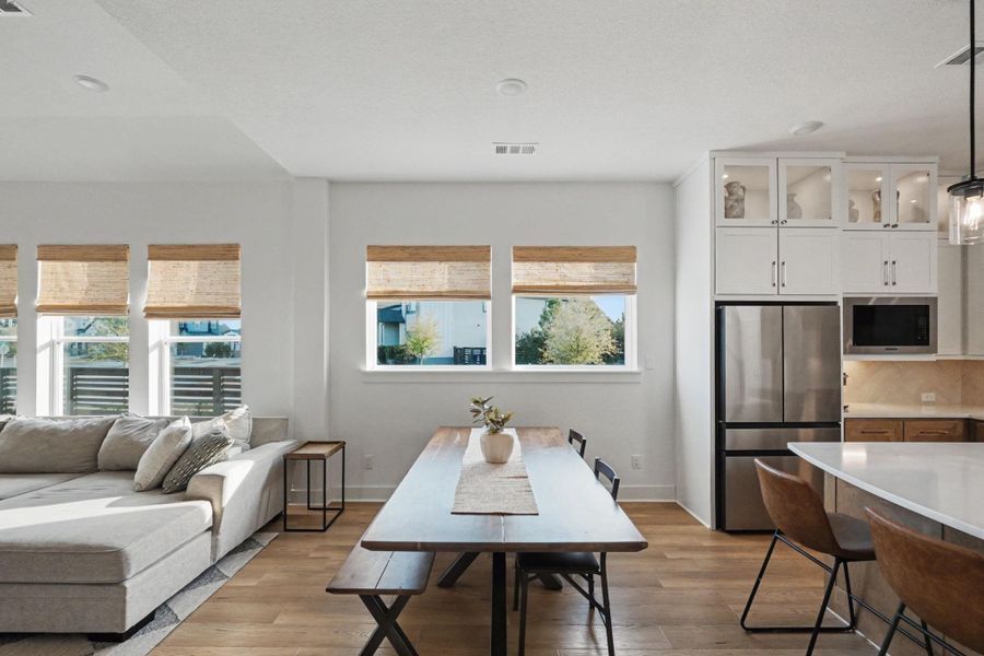 Beautifully designed open dining and living area with warm wood flooring and abundant natural light. The seamless flow into the chef-inspired kitchen creates an inviting, upscale space ideal for both intimate dinners and effortless entertaining.