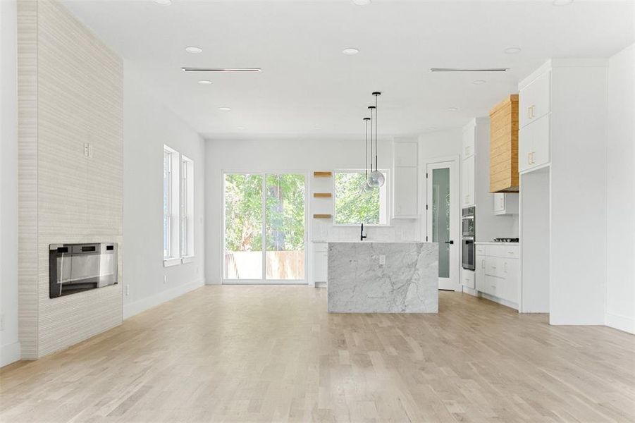 Kitchen with white cabinetry, a fireplace, a kitchen island, light wood-type flooring, and pendant lighting